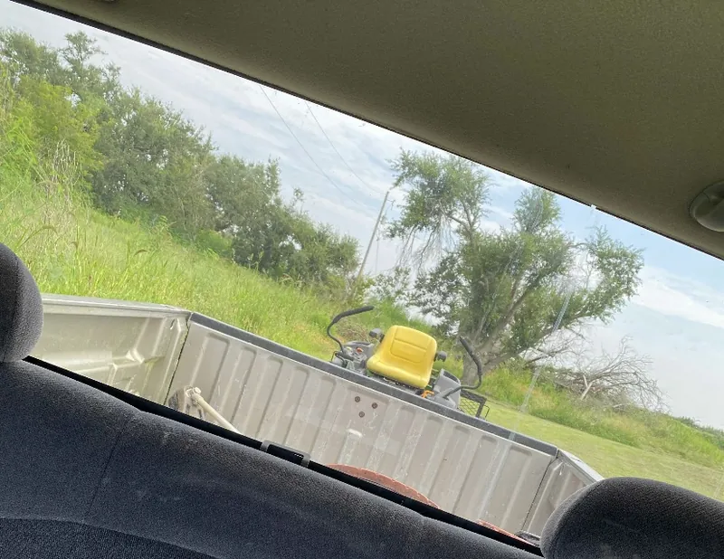 Photo from inside Collin's truck of a riding mower loaded in the truck bed, from his lawn care days