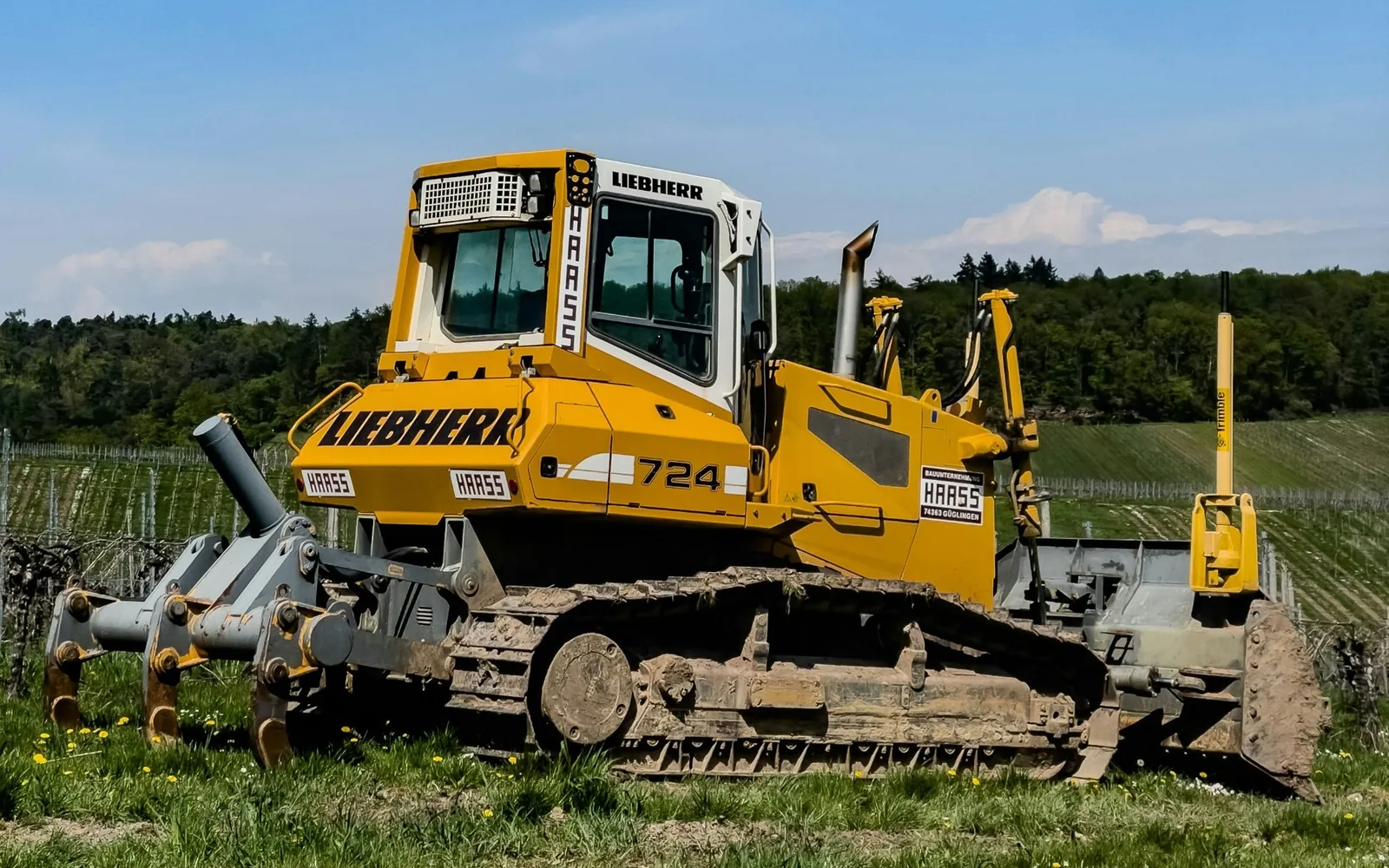 Photo of a yellow bulldozer parked in a green field, for a post on contractor website cost