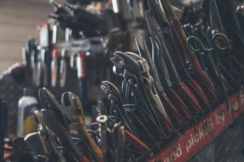 Photo of a rack of well-used pliers and wrenches in a plumbing workshop